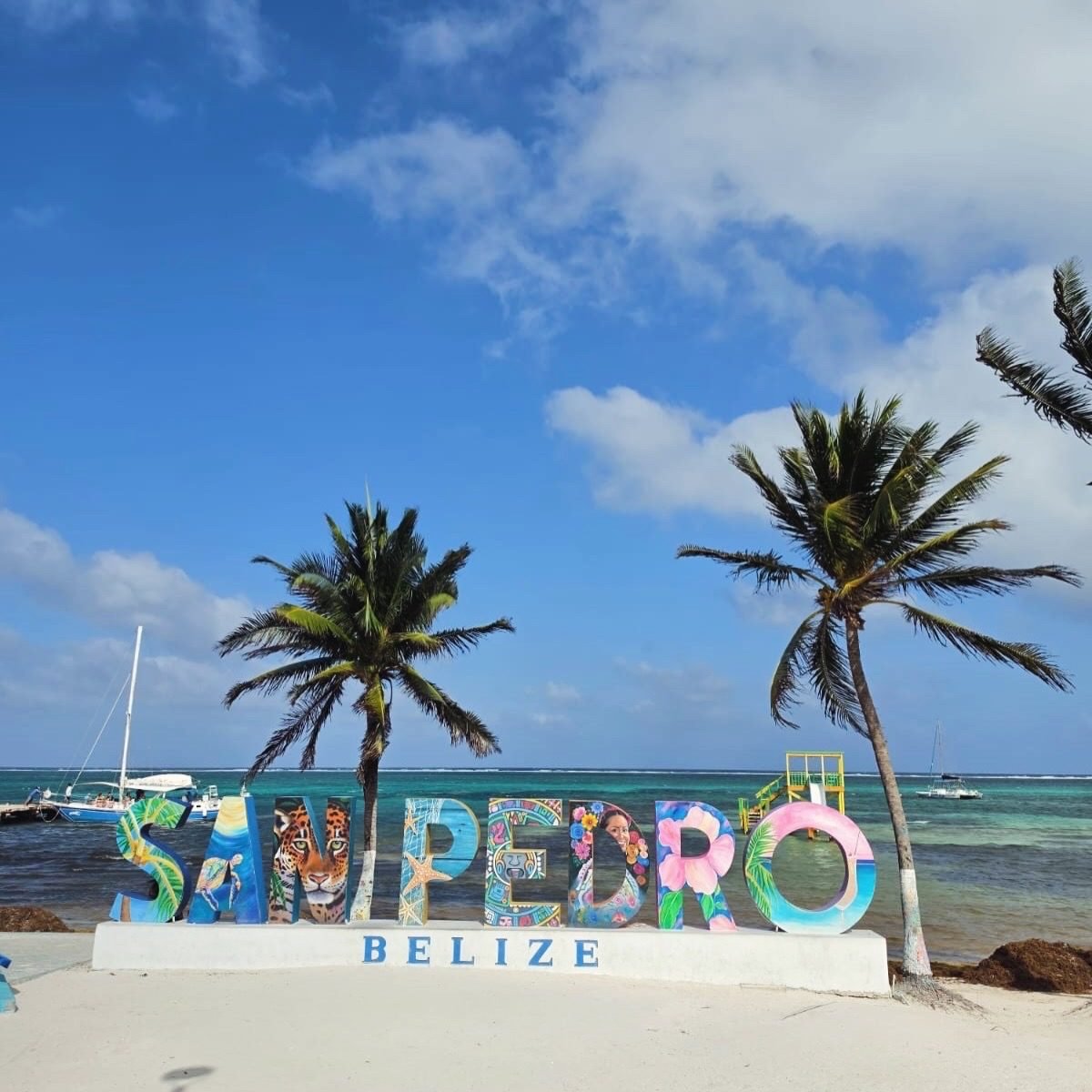 Letrero colorido de San Pedro Belize en la playa con palmeras